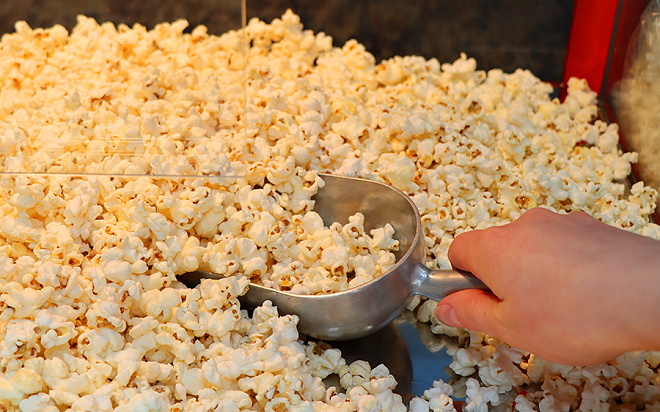 A close up photo of popcorn being scooped up