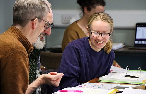 smiling lady sitting at a desk in convocation with other members