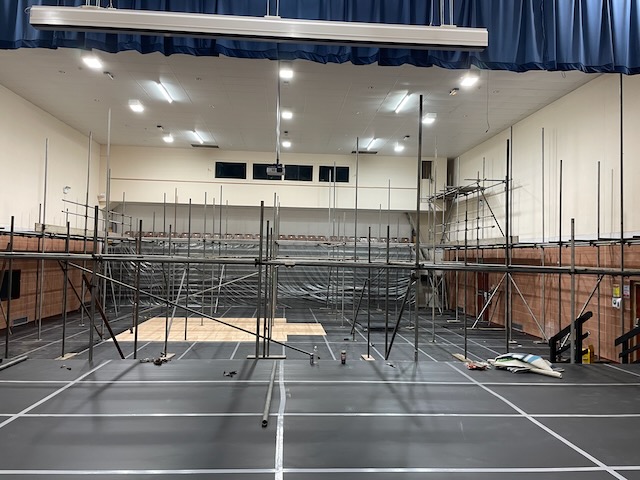 Neuadd yn cael ei uwchraddio gyda sgaffaldiau metel wedi'u gosod ar draws y llawr, gorchudd plastig wedi'i godi dros gadeiriau tynnu allan wedi'u pentyrru yn y cefndir