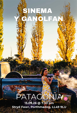 A young woman bathed in sunshine leans on a truck looking at the camera. A man gazes into the distance as he sits on the rusty truck.