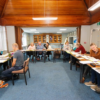 dosbaeth gyda byrddau ag pobl yn gweithio